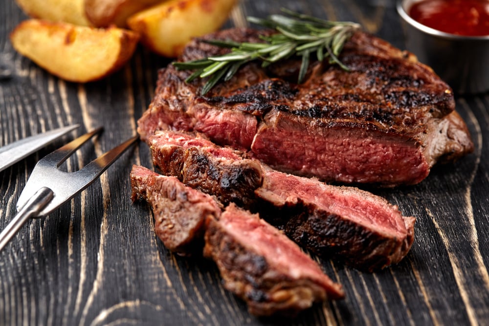 Juicy steak medium rare beef with spices on wooden board on table — Stock Photo, Image