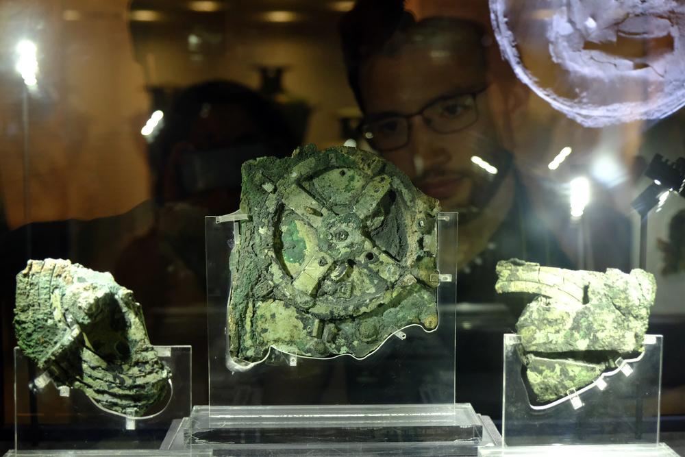 Visitors look at a fragment of the 2,100-year-old Antikythera Mechanism, believed to be the earliest surviving mechanical computing device, is seen at the National Archaeological Museum in Athens, Greece on Aug. 26, 2018 — Photo by Ale_Mi